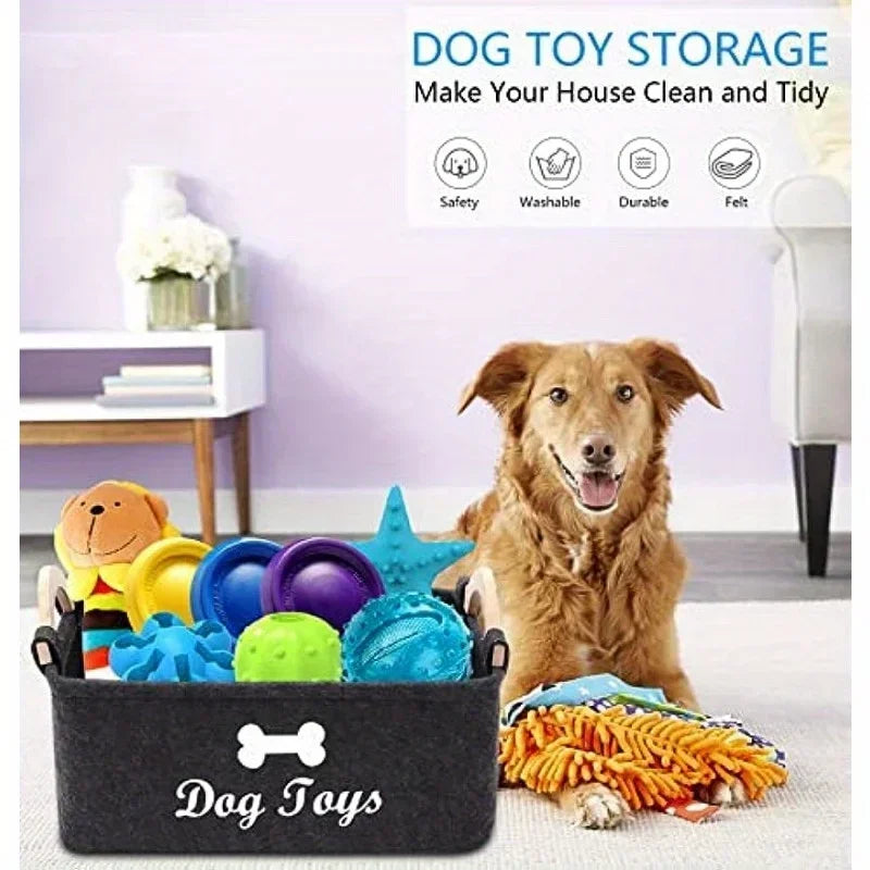A black felt storage basket labeled Dog Toys filled with various colorful dog toys on a white surface.