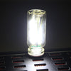 A clear glass accent light bulb resting on a black grid surface.