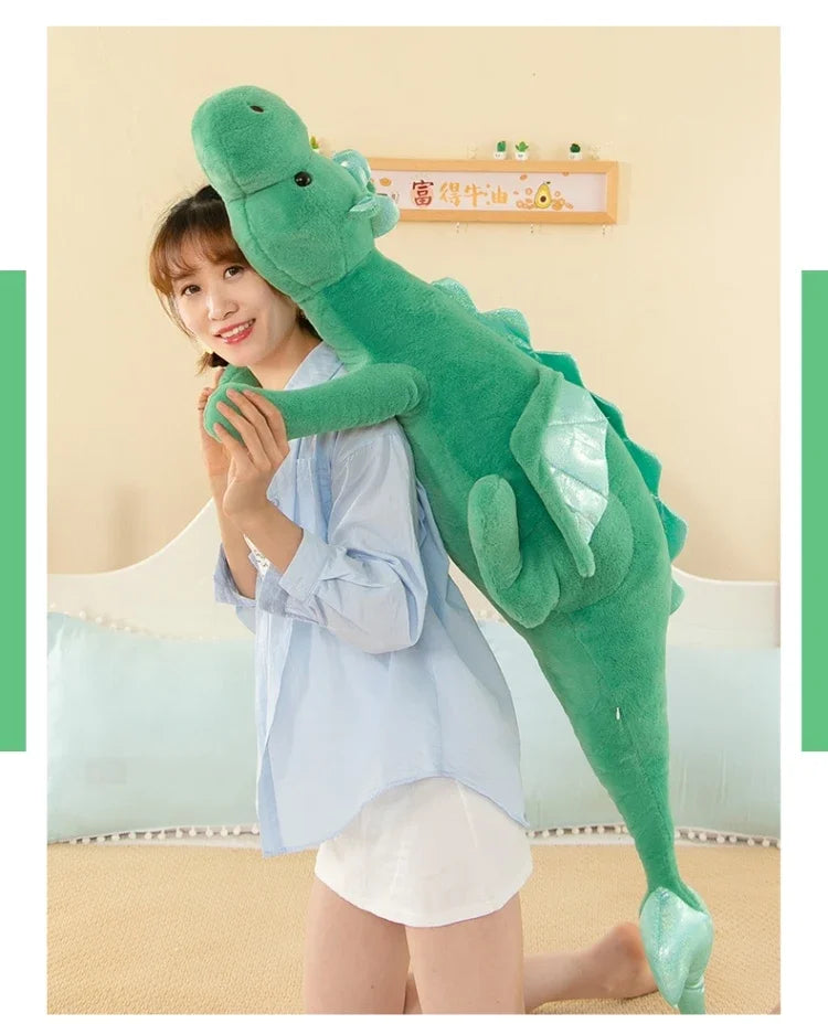 A woman is holding a large, green dragon plush toy against her chest in a light blue shirt.