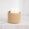 A natural beige handwoven cotton rope storage basket filled with white tissue paper, used for desk organization.