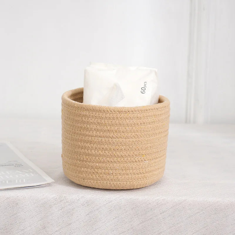 A natural beige handwoven cotton rope storage basket filled with white tissue paper, used for desk organization.