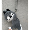 A gray and white plush toy resembling a stylized animal face is hanging against a gray textured background.