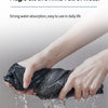 A hand is squeezing a dark cloth that is dripping water, demonstrating strong water absorption.