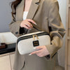 Eine Frau hält eine elegante beige Reise-Make-up-Organizer-Tasche mit goldenen Akzenten und einer maßgeschneiderten Jacke.