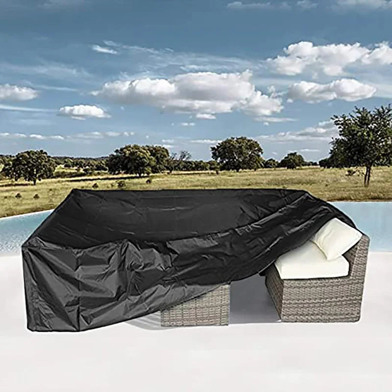 Black waterproof patio furniture cover placed on a white surface with a wicker cushion.