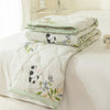 A white quilted summer quilt featuring a floral pattern with black and white panda designs on a bed.