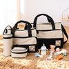 A beige and black multifunctional diaper bag set with various accessories like bottles and toys