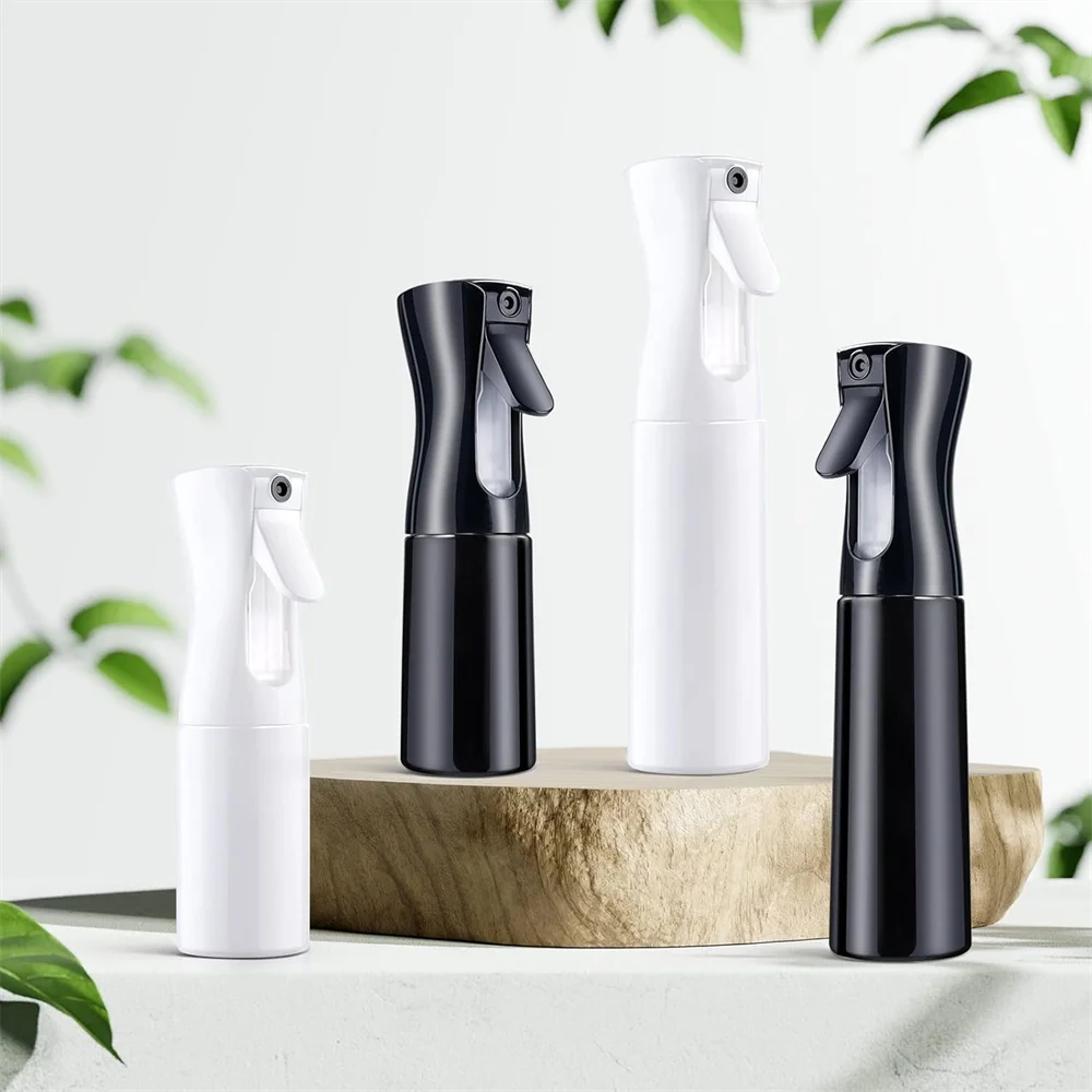 A set of three black and white continuous fine mist spray bottles displayed on a wooden surface.