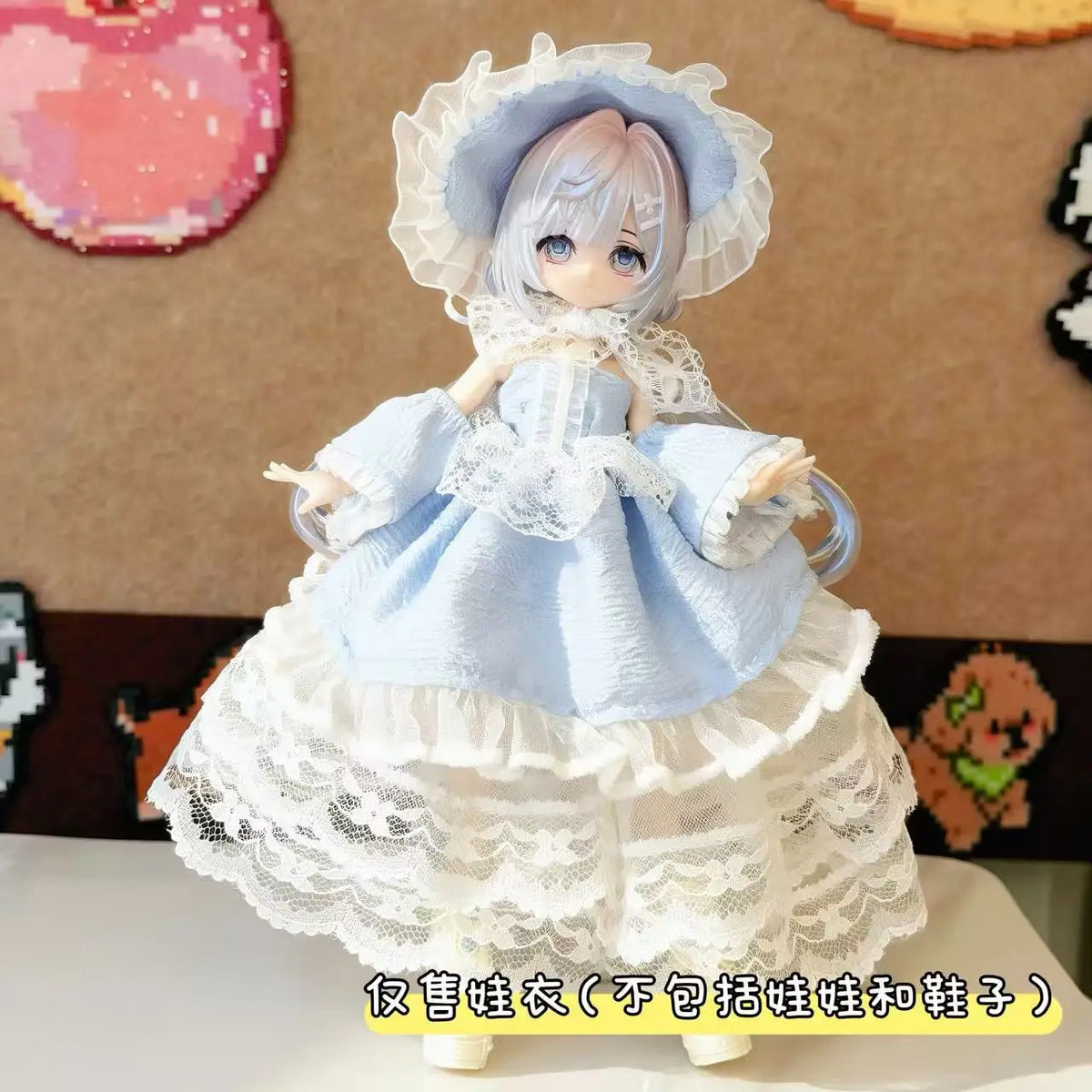 A light blue dress outfit for a doll featuring lace and frills, displayed against a brown background.