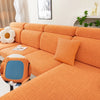 Asiento y funda elástica naranja con patrón de rejilla en un sofá de color claro.
