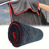 A rolled black microfiber drying towel with red trim is shown next to a car door.