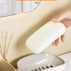 A white double-layered draining soap dish is shown being held and placed on a white surface.