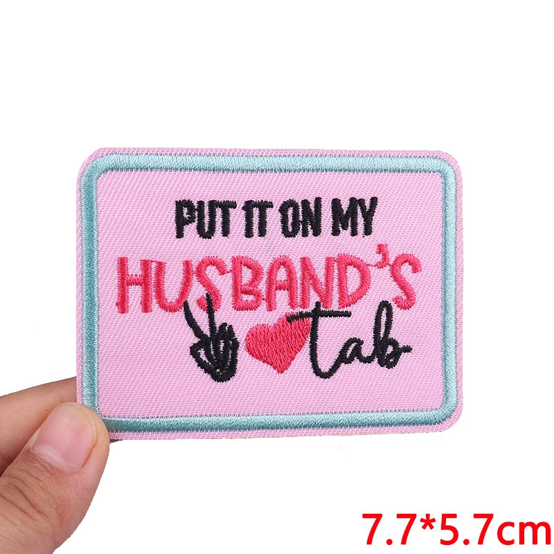 Pink embroidered patch with black text saying Put it on my husband's tab
