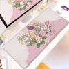 A pink kawaii cartoon gaming desk mat featuring cute woodland animals and flowers with a non-slip rubber base.