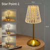 A tall, gold-toned crystal touch table lamp with a textured shade and slender stand on a wooden surface.