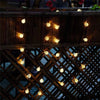 String lights with glowing orbs are draped across a dark wooden structure and lattice work.