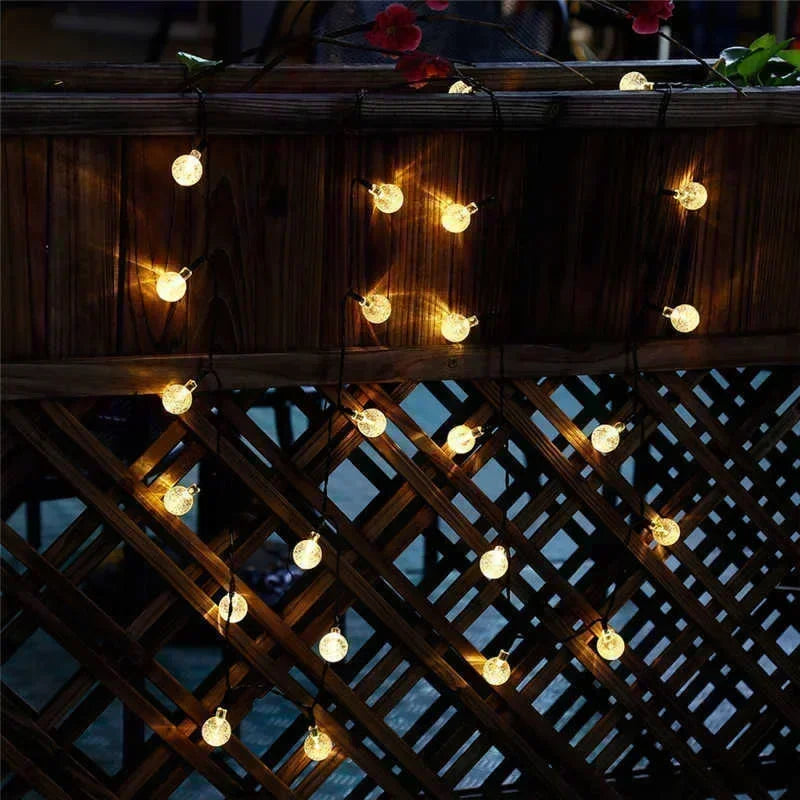 String lights with glowing orbs are draped across a dark wooden structure and lattice work.