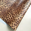 A close-up view of leopard print self-adhesive wallpaper sheet with a grid ruler visible.