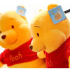 A yellow Winnie the Pooh plush toy wearing a red shirt and a blue badge.