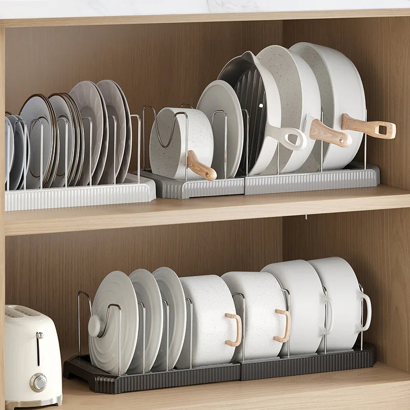 A wooden shelf displaying a silver and white expandable pot and pan organizer rack with adjustable dividers.