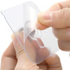 A hand is holding a clear self-adhesive silicone or plastic sheet with a cutout shape, likely for storage or crafting.