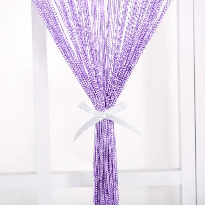 Purple beaded thread curtain tied with a white ribbon hanging vertically.