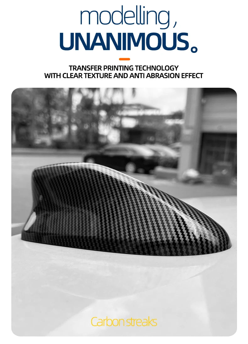 Close-up of a black carbon streak antenna cover placed on a white car surface.