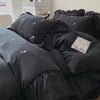 A black duvet cover set with rose embroidery and lace details is displayed on a bed.