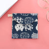 A dark blue cosmetic storage pouch with a white pattern featuring various animal and floral motifs, resting on a pink surface