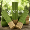 A stack of green citronella incense sticks with natural bamboo tips on a wooden surface.