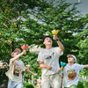 Three children playing outdoors with flying saucer toys in a grassy park setting.