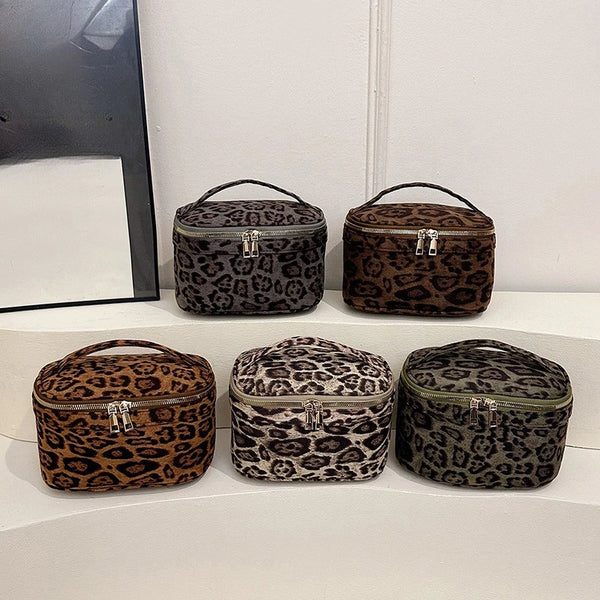Four faux suede cosmetic bags in leopard print are displayed on a white surface.