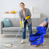 A woman is using a blue rolling mop bucket and pole to clean a floor.