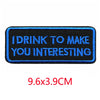 A rectangular dark blue embroidered iron-on letter patch with white text that reads I DRINK TO MAKE YOU INTERESTING