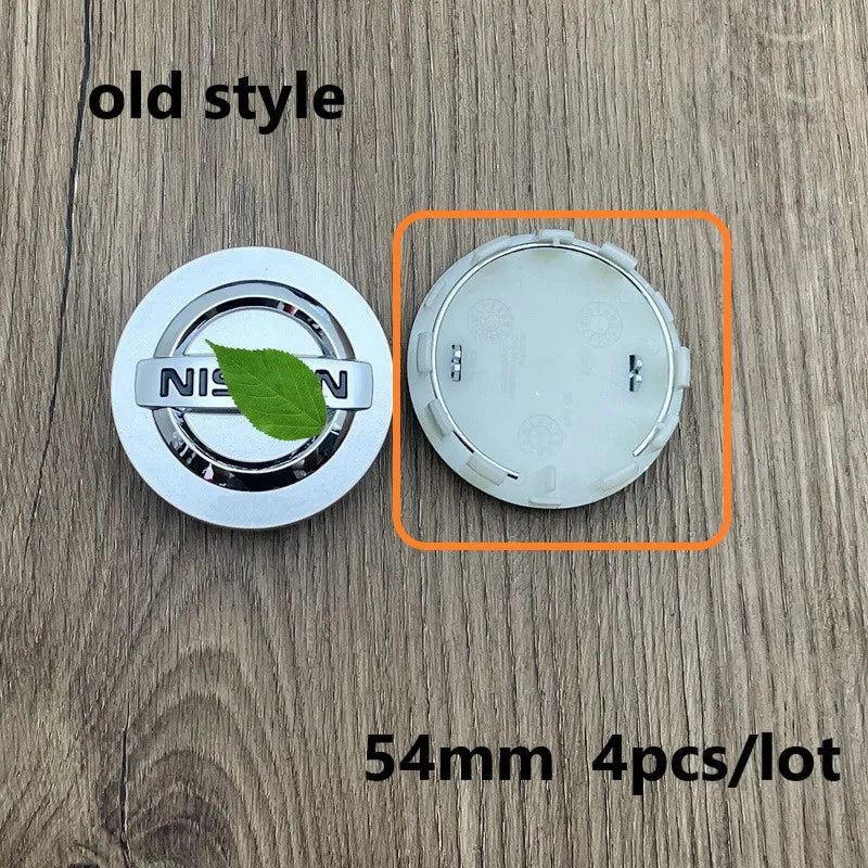 A set of four 54mm wheel center hub caps for Nissan models shown on a wooden surface.