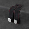 Black suede storage hooks with silver accents designed for hanging bags or items on a car seat back.