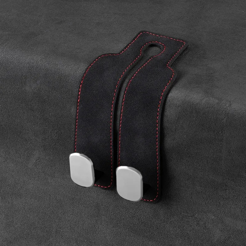 Black suede storage hooks with silver accents designed for hanging bags or items on a car seat back.