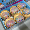 Eine Box mit Regenbogenperlen-Dumplings, Squishy-Fidget-Spielzeug mit bunten Kugeln in gelben Tassen.
