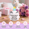 A handmade crochet unicorn doll with pink and purple accents sitting on a wooden surface.
