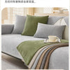 A solid olive green chenille non-slip sofa cover is draped over a gray sofa, showing various fabric textures.