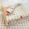 A stack of cartoon pattern kids lightweight summer quilts in pale yellow and pink checkered fabric.