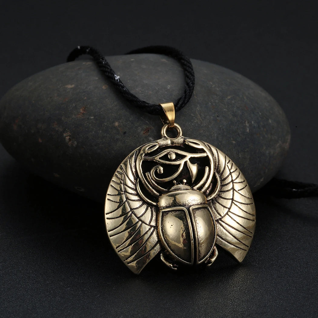 A silver ancient Egyptian scarab pendant necklace is displayed on a dark stone.
