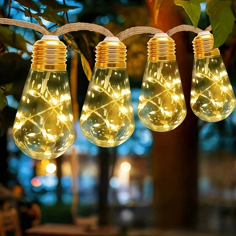 String lights with warm yellow bulbs hanging from a rope, illuminating foliage in the evening.