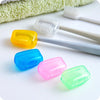 Colorful protective toothbrush heads and a white plastic brush are displayed on a white surface.