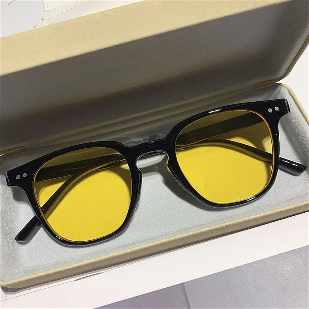 Vintage square sunglasses with yellow lenses resting in a light-colored box.