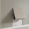 A close-up of a beige vertical striped wallpaper with a rectangular, vertically striped roll mounted on the wall.