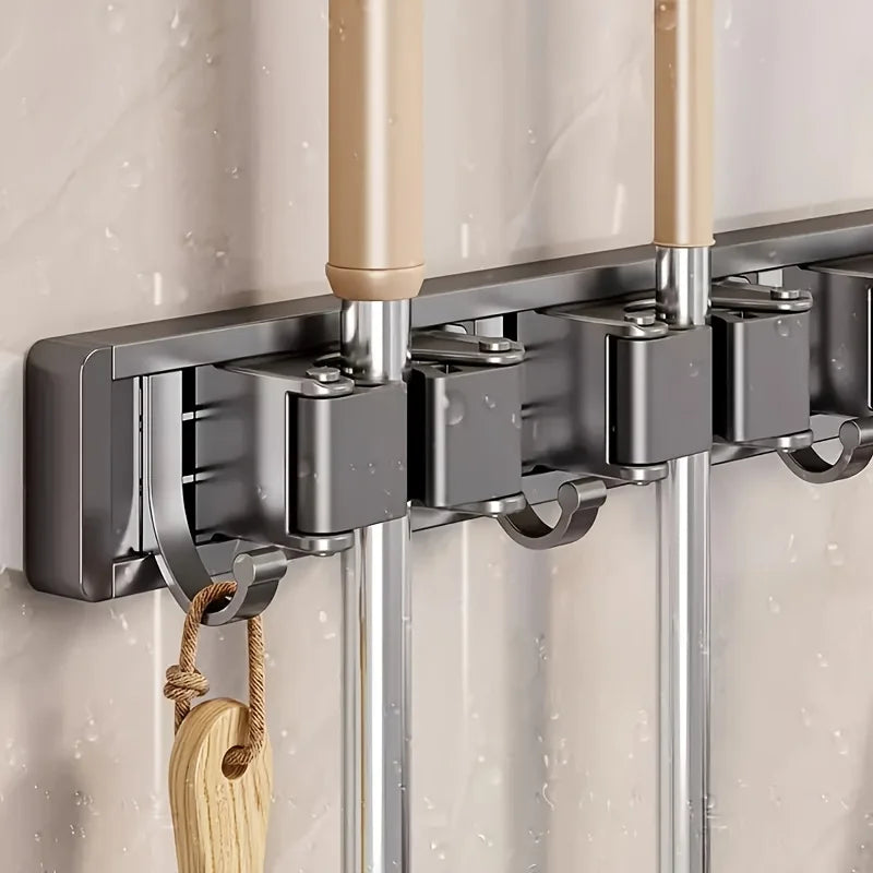 A wall-mounted metal holder for a mop and broom with detachable hooks, featuring silver and beige components.