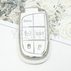 A silver plastic car key fob with panic and unlock buttons is shown against a patterned background.
