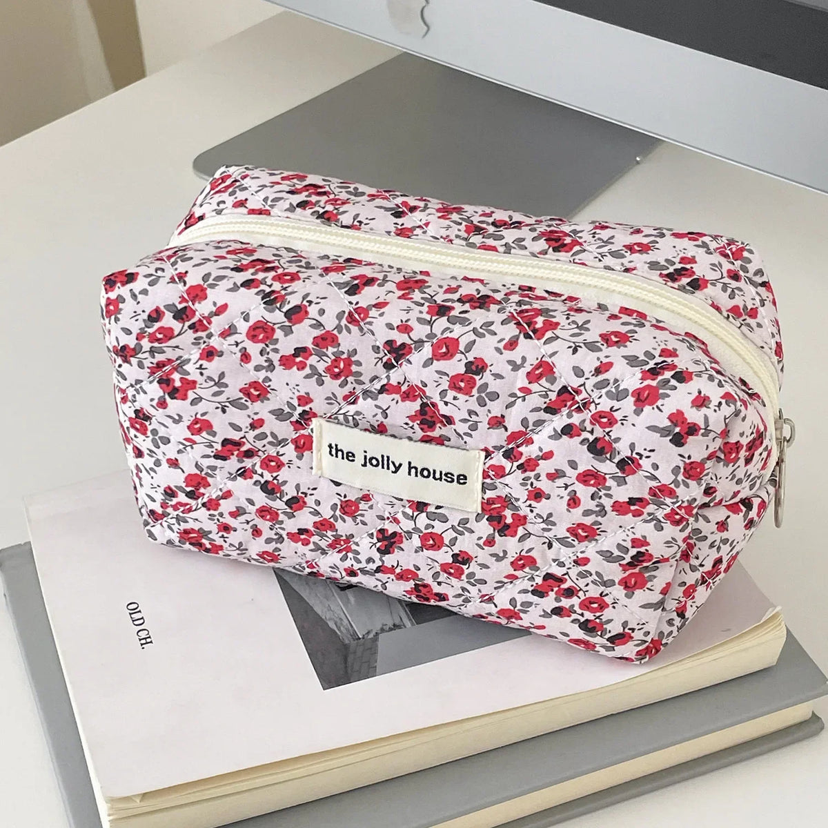 A floral quilted makeup bag with a zipper closure featuring red and pink roses on a white background.
