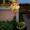 A solar owl garden light with a crescent moon and glass orb decoration mounted on a wall.